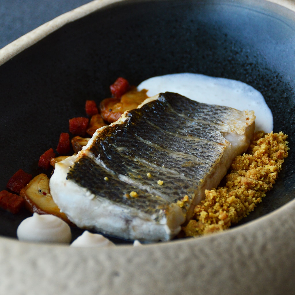 Lup de mare, chorizo cuburi, porcini caramelizate cu sweet chilli, piure de fasole alba, spuma cu Yuzu